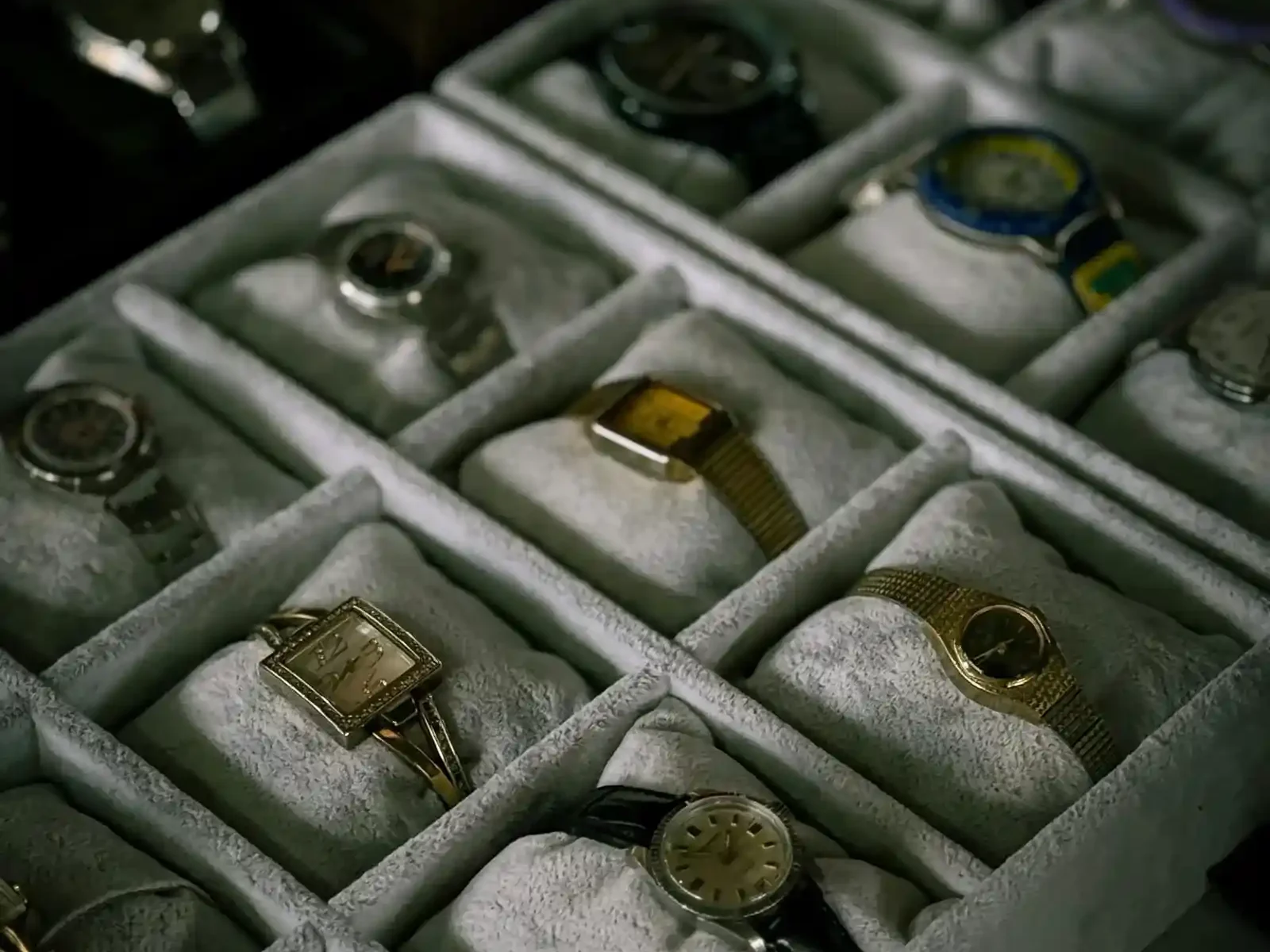 A curated collection of vintage and luxury wristwatches displayed in a professional grey velvet watch organizer box.